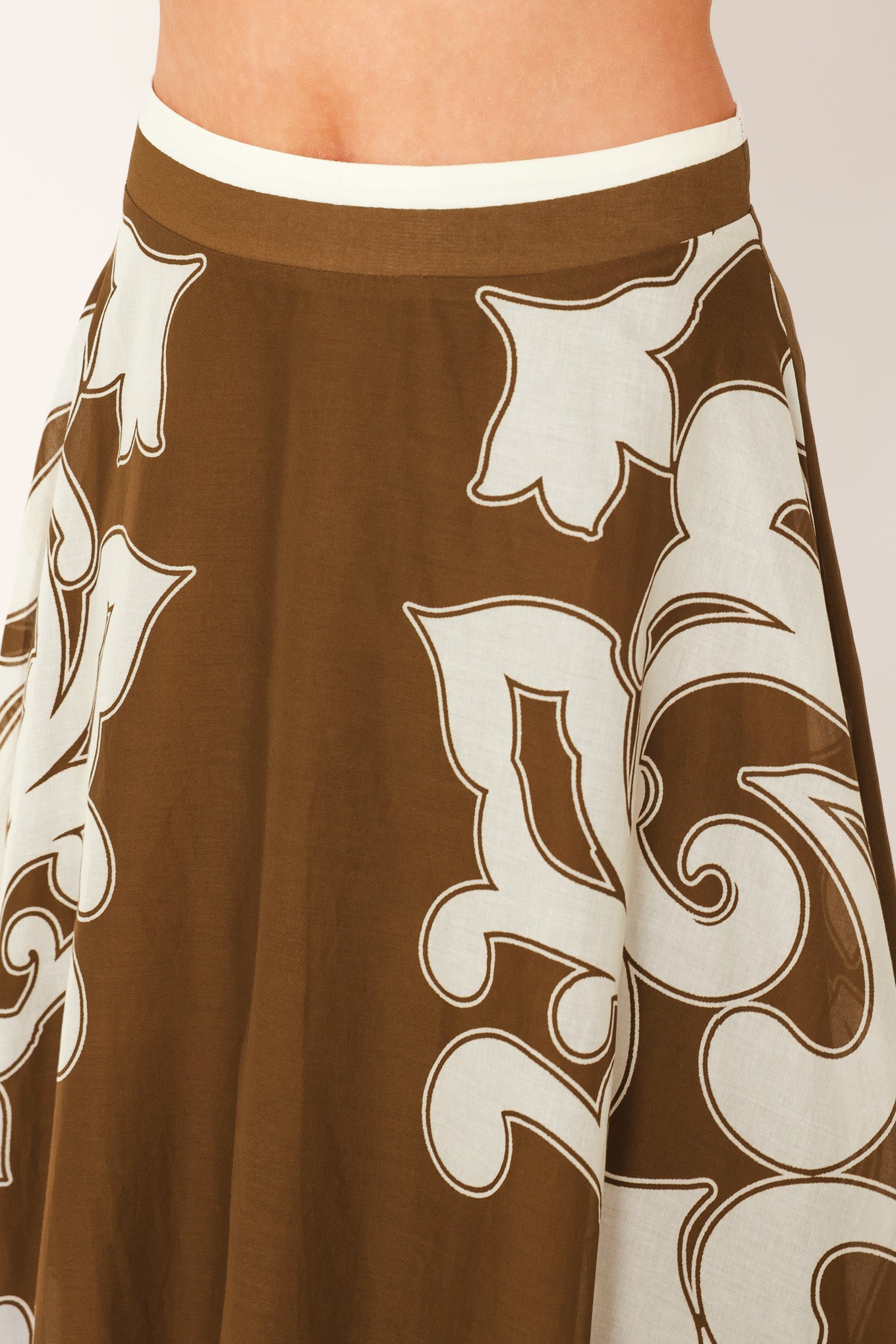 A woman wearing a brown midi skirt with a large white baroque pattern | Flying Tomato