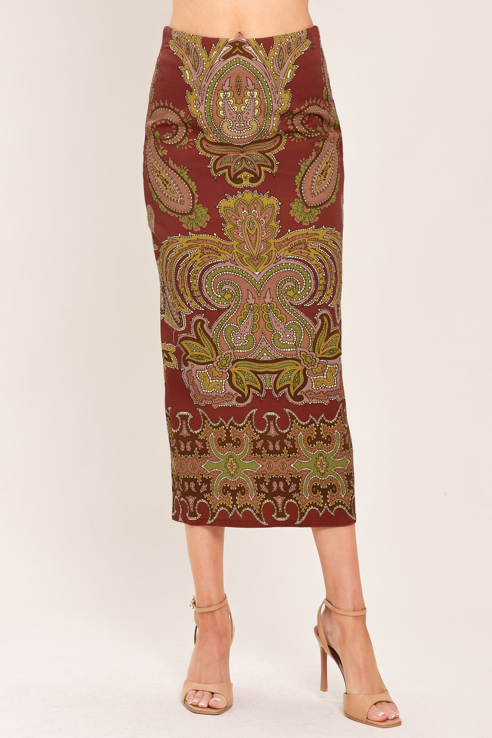 A woman wearing a midi skirt with an ornate paisley pattern in rust red, gold, and olive green | Flying Tomato
