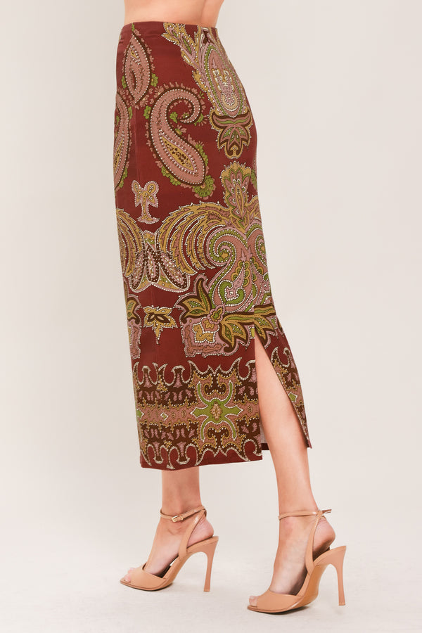 A woman wearing a midi skirt with an ornate paisley pattern in rust red, gold, and olive green | Flying Tomato