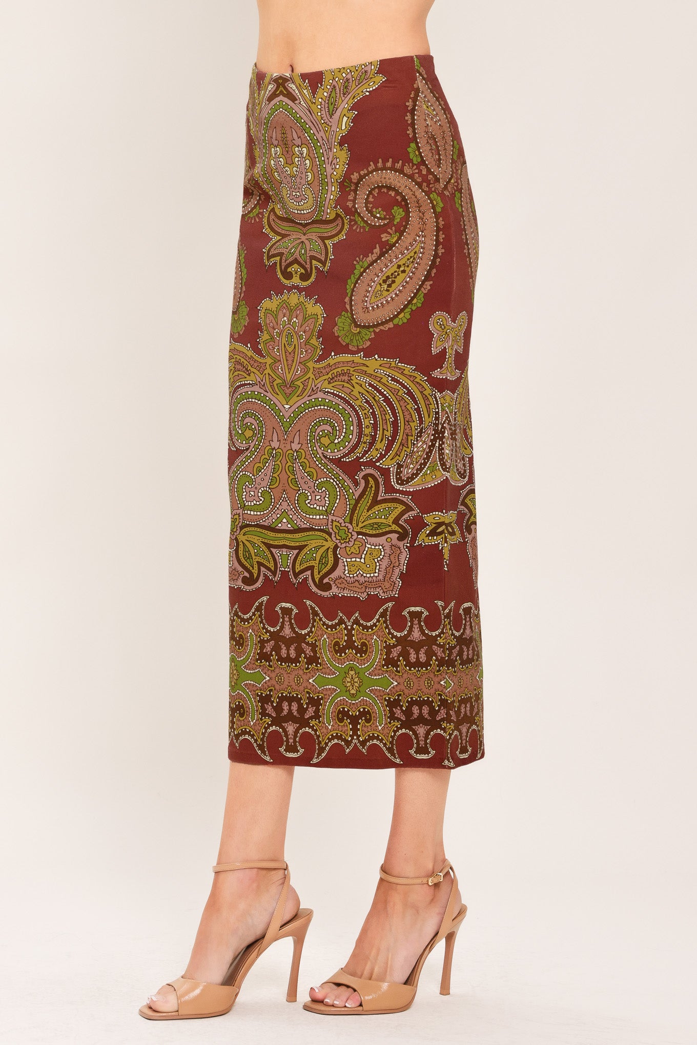 A woman wearing a midi skirt with an ornate paisley pattern in rust red, gold, and olive green | Flying Tomato