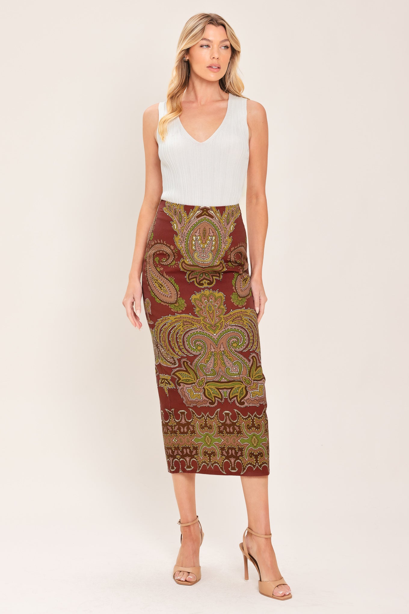 A woman wearing a midi skirt with an ornate paisley pattern in rust red, gold, and olive green | Flying Tomato