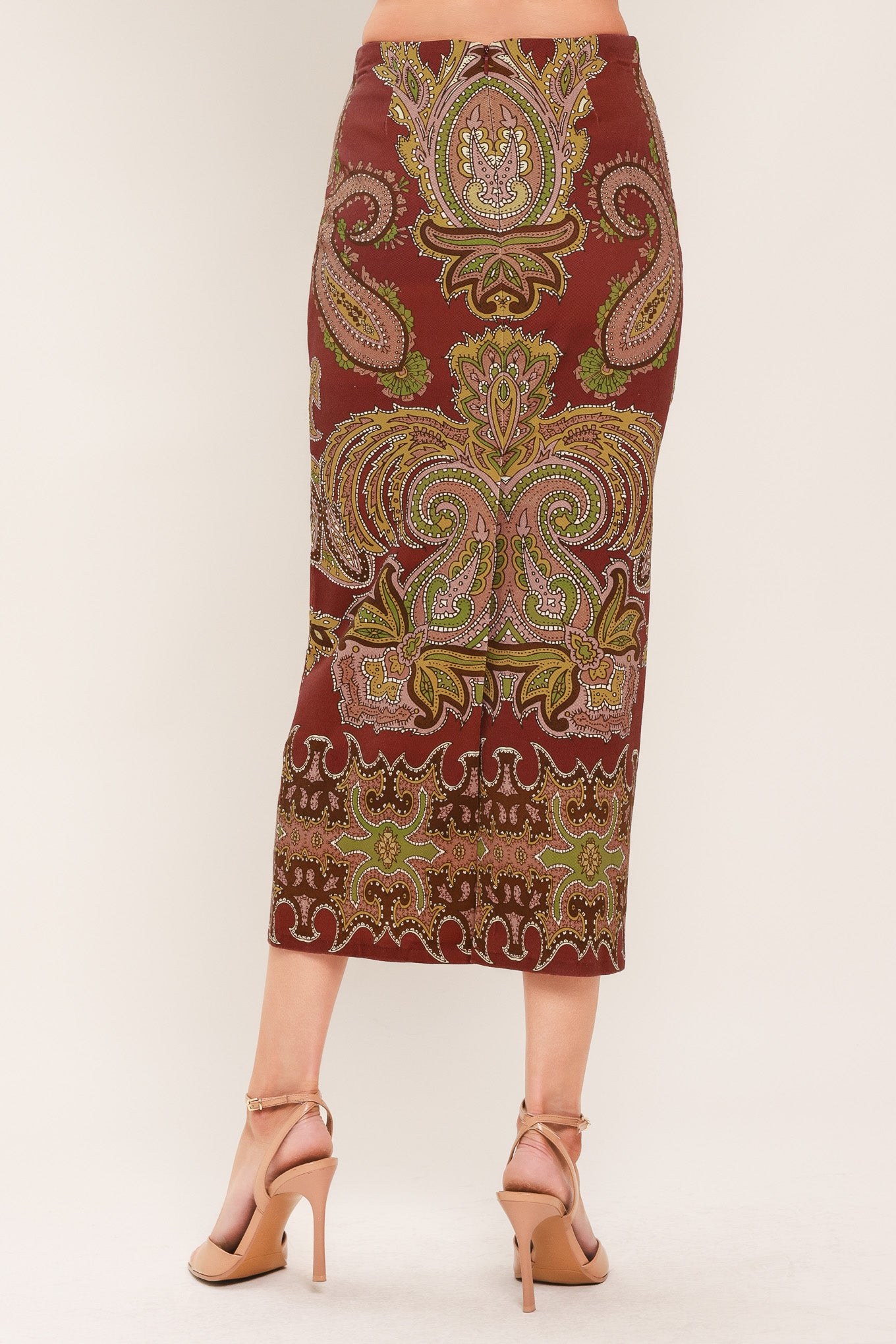 A woman wearing a midi skirt with an ornate paisley pattern in rust red, gold, and olive green | Flying Tomato