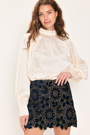 Woman wearing a navy blue velvet high-waisted mini skirt with gold floral lace over | Flying Tomato