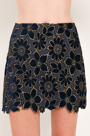 Woman wearing a navy blue velvet high-waisted mini skirt with gold floral lace over | Flying Tomato