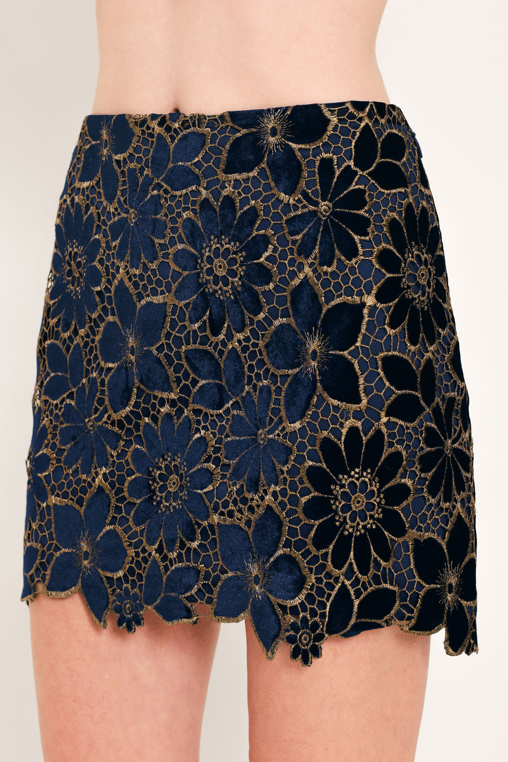 Woman wearing a navy blue velvet high-waisted mini skirt with gold floral lace over | Flying Tomato