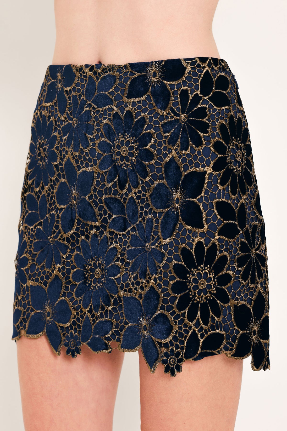 Woman wearing a navy blue velvet high-waisted mini skirt with gold floral lace over | Flying Tomato