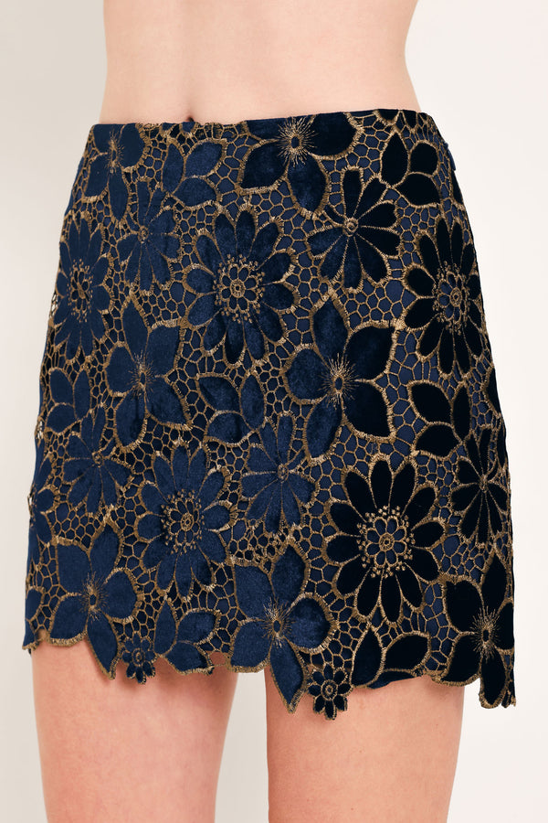 Woman wearing a navy blue velvet high-waisted mini skirt with gold floral lace over | Flying Tomato