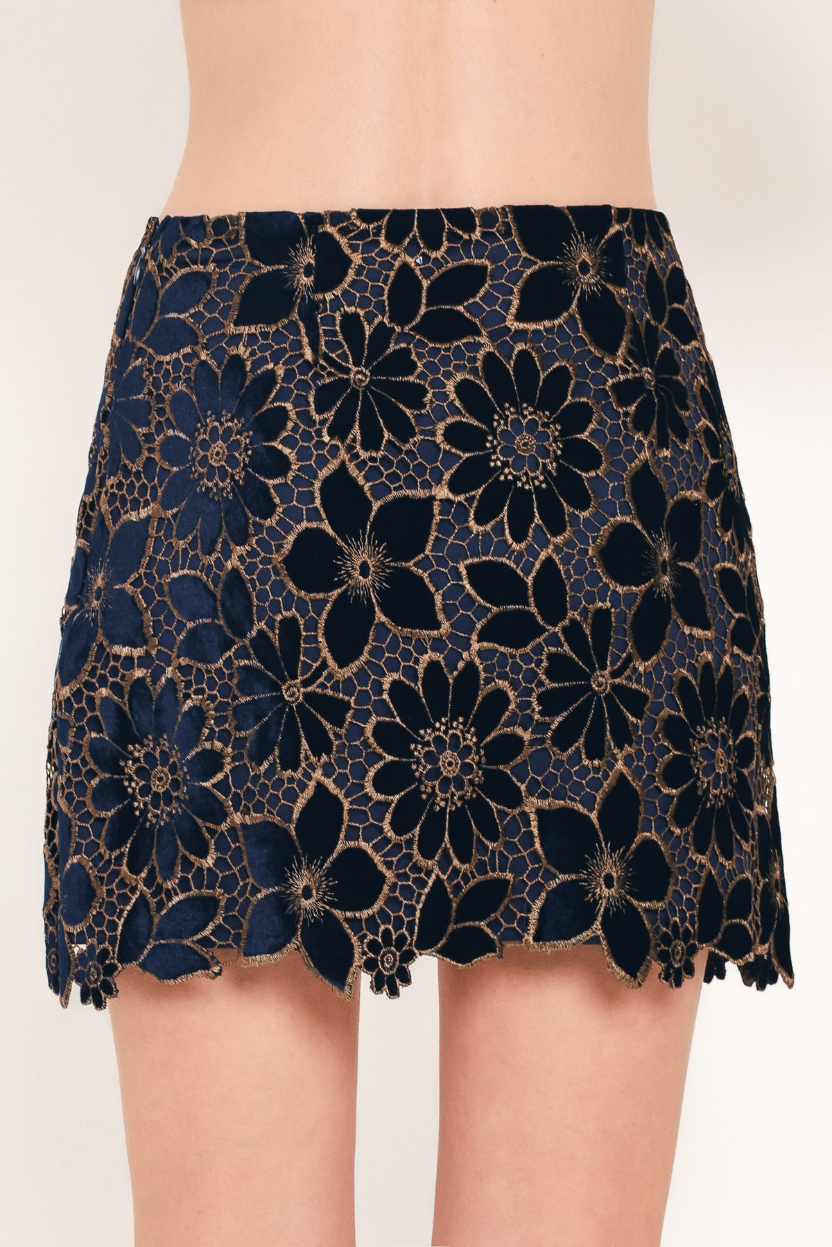 Woman wearing a navy blue velvet high-waisted mini skirt with gold floral lace over | Flying Tomato