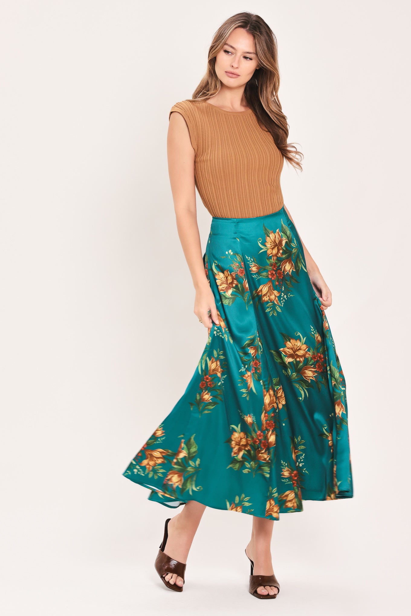 A woman wearing a teal green midi skirt with a vibrant orange and yellow floral print | Flying Tomato