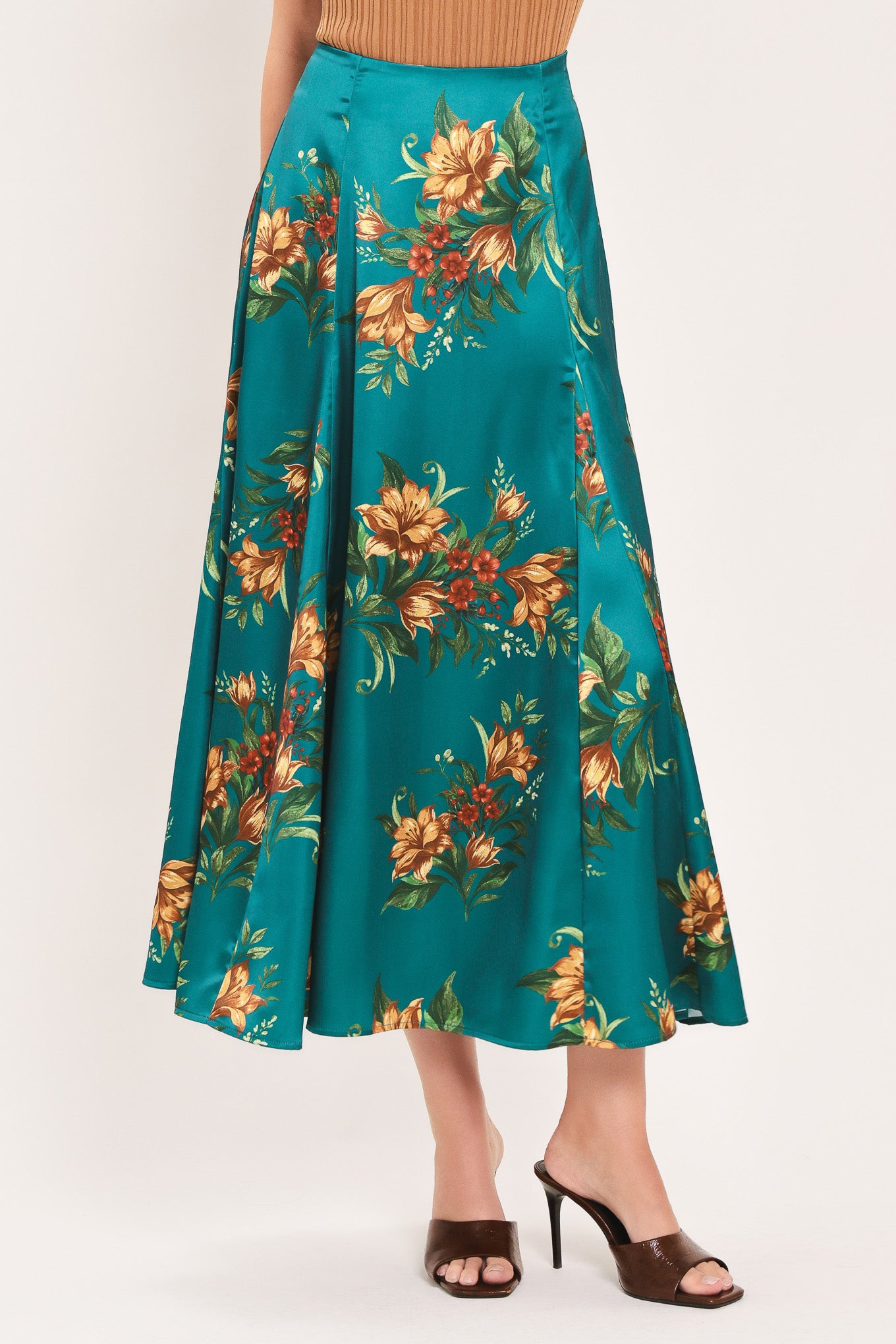 A woman wearing a teal green midi skirt with a vibrant orange and yellow floral print | Flying Tomato