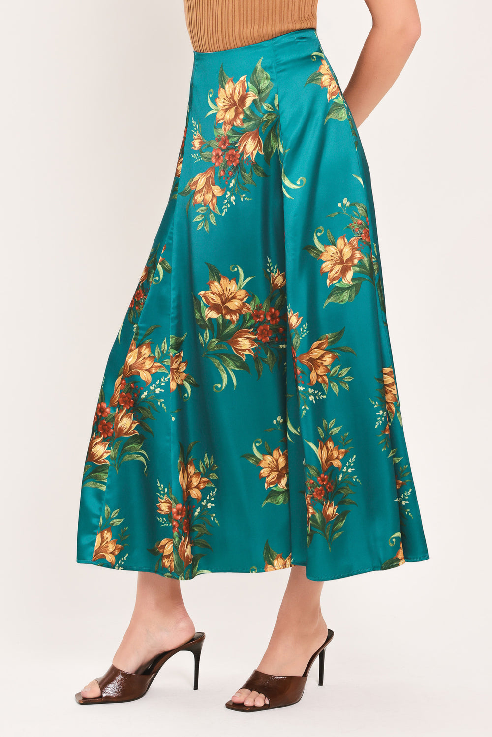 A woman wearing a teal green midi skirt with a vibrant orange and yellow floral print | Flying Tomato