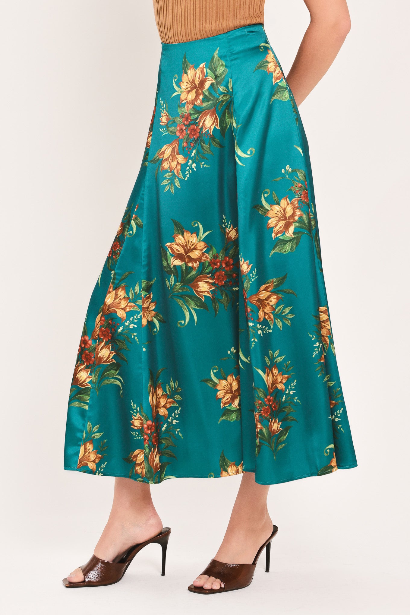 A woman wearing a teal green midi skirt with a vibrant orange and yellow floral print | Flying Tomato