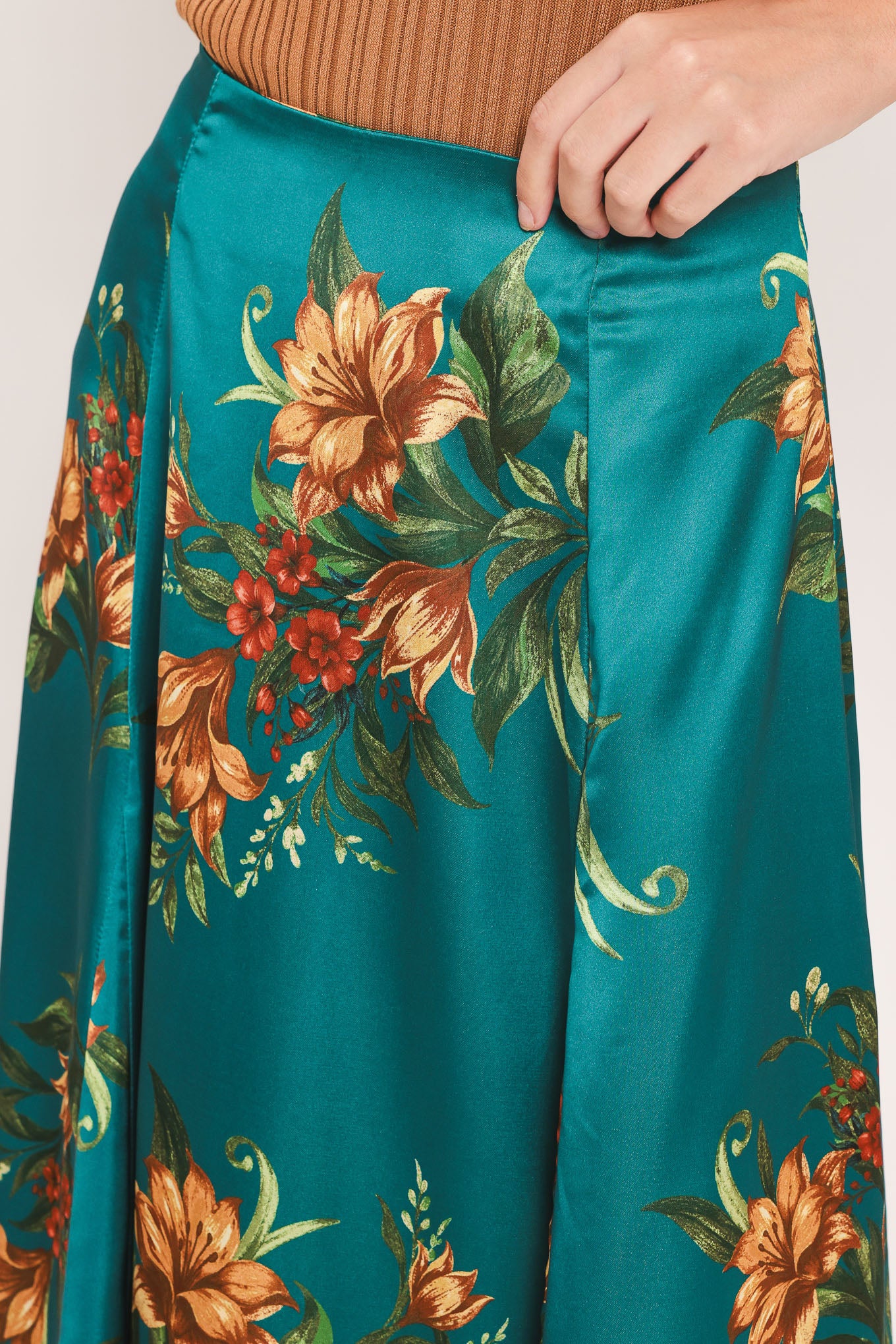 A woman wearing a teal green midi skirt with a vibrant orange and yellow floral print | Flying Tomato