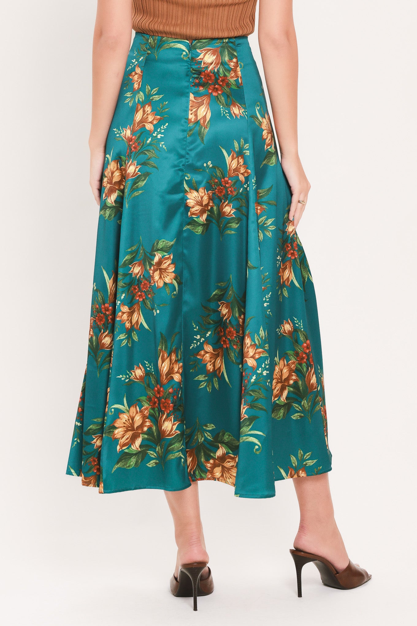 A woman wearing a teal green midi skirt with a vibrant orange and yellow floral print | Flying Tomato