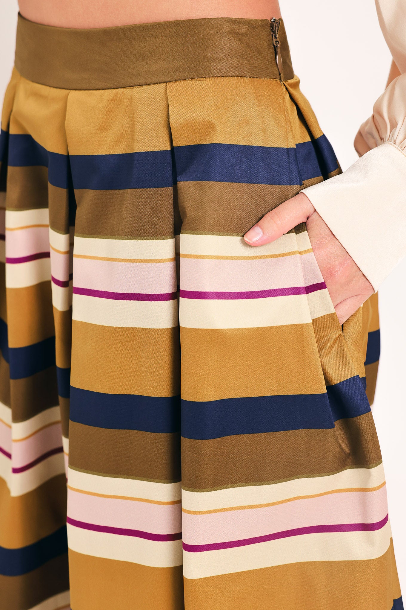 Woman wearing a multicolored beige, mustard yellow, navy blue, and burgundy striped midi skirt with pleats and pockets | Flying Tomato