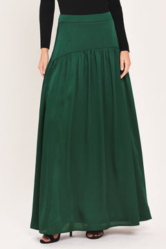 A dark hunter green satin-like maxi skirt with a drop waist worn by a model | Flying Tomato