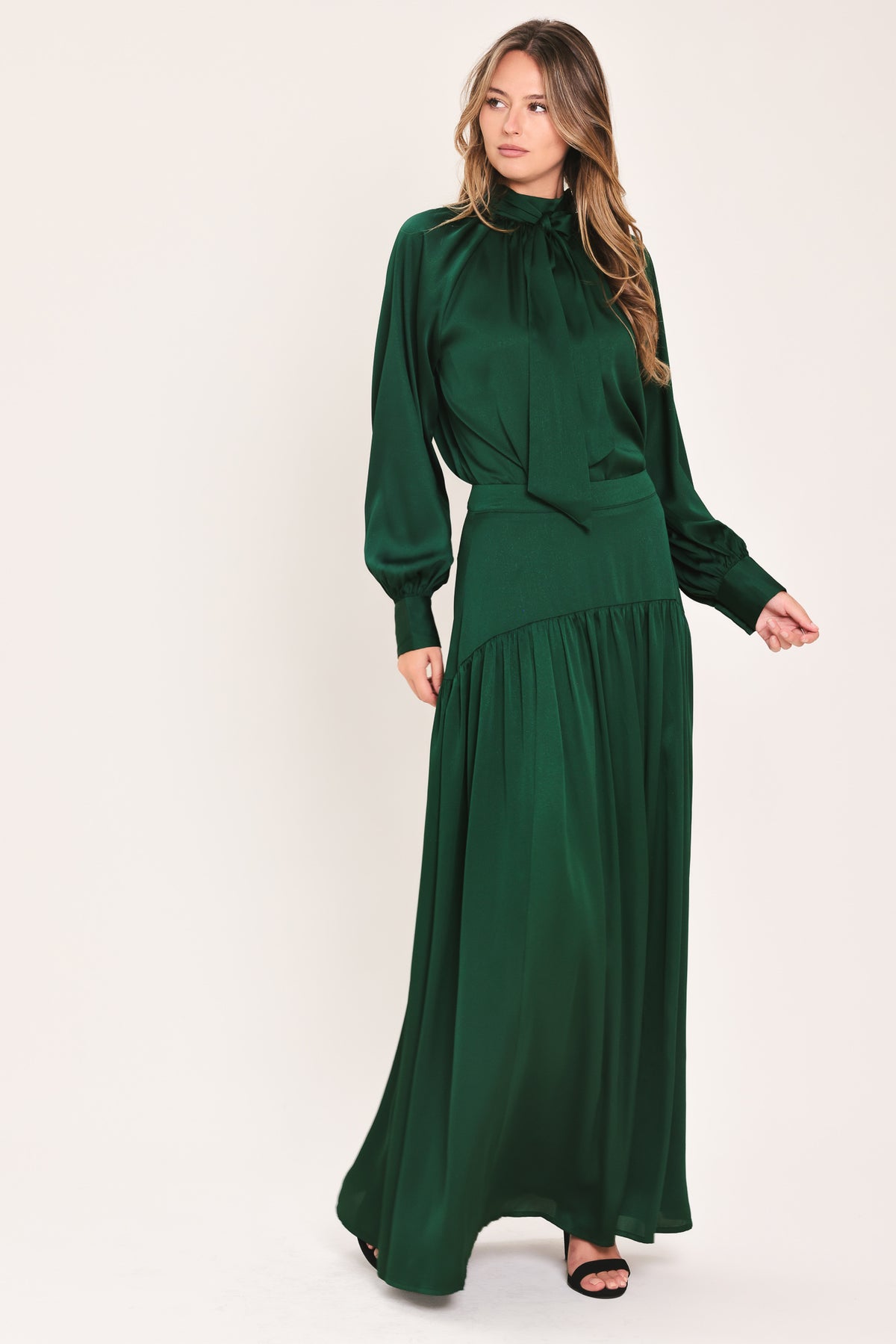 A dark hunter green satin-like maxi skirt with a drop waist worn by a model | Flying Tomato