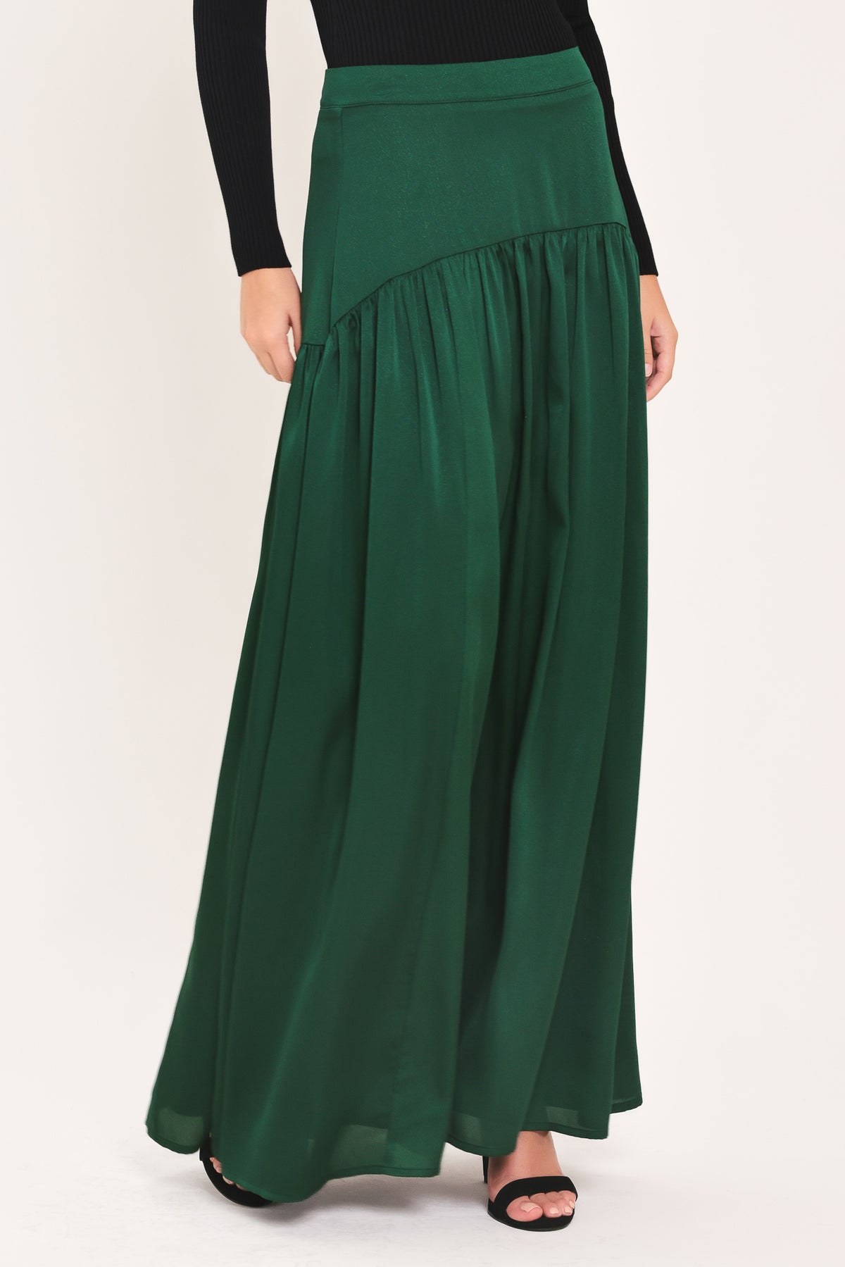 A dark hunter green satin-like maxi skirt with a drop waist worn by a model | Flying Tomato