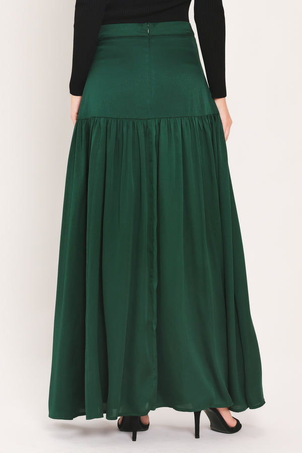 A dark hunter green satin-like maxi skirt with a drop waist worn by a model | Flying Tomato
