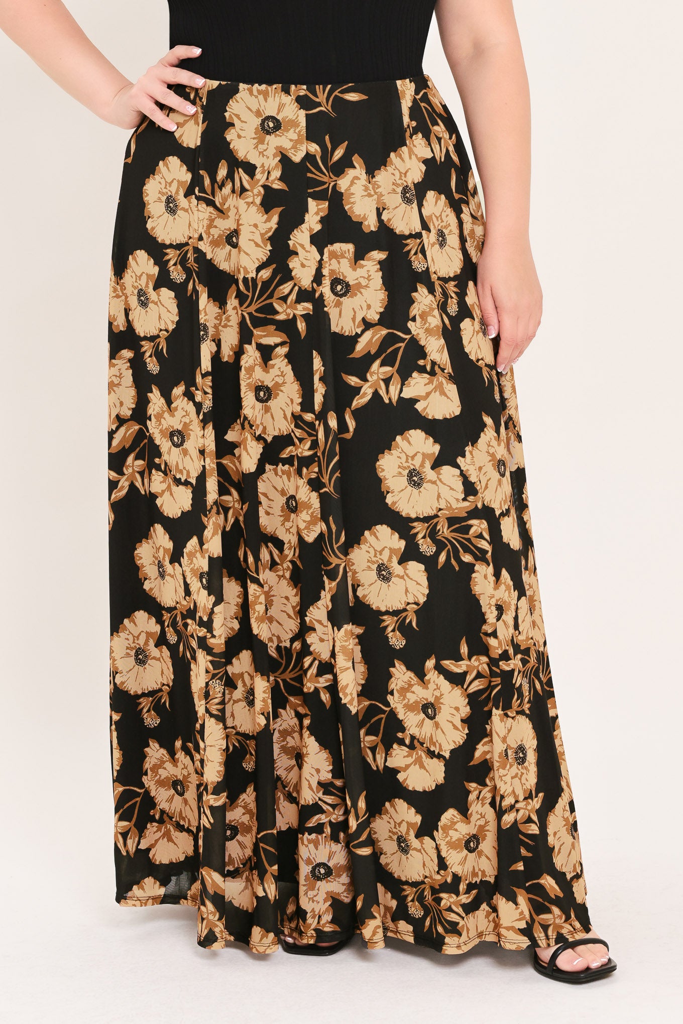 A woman modeling a sleeveless black top paired with a long black skirt featuring a large beige floral print | Plus Curve Flying Tomato