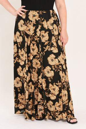 A woman modeling a sleeveless black top paired with a long black skirt featuring a large beige floral print | Plus Curve Flying Tomato
