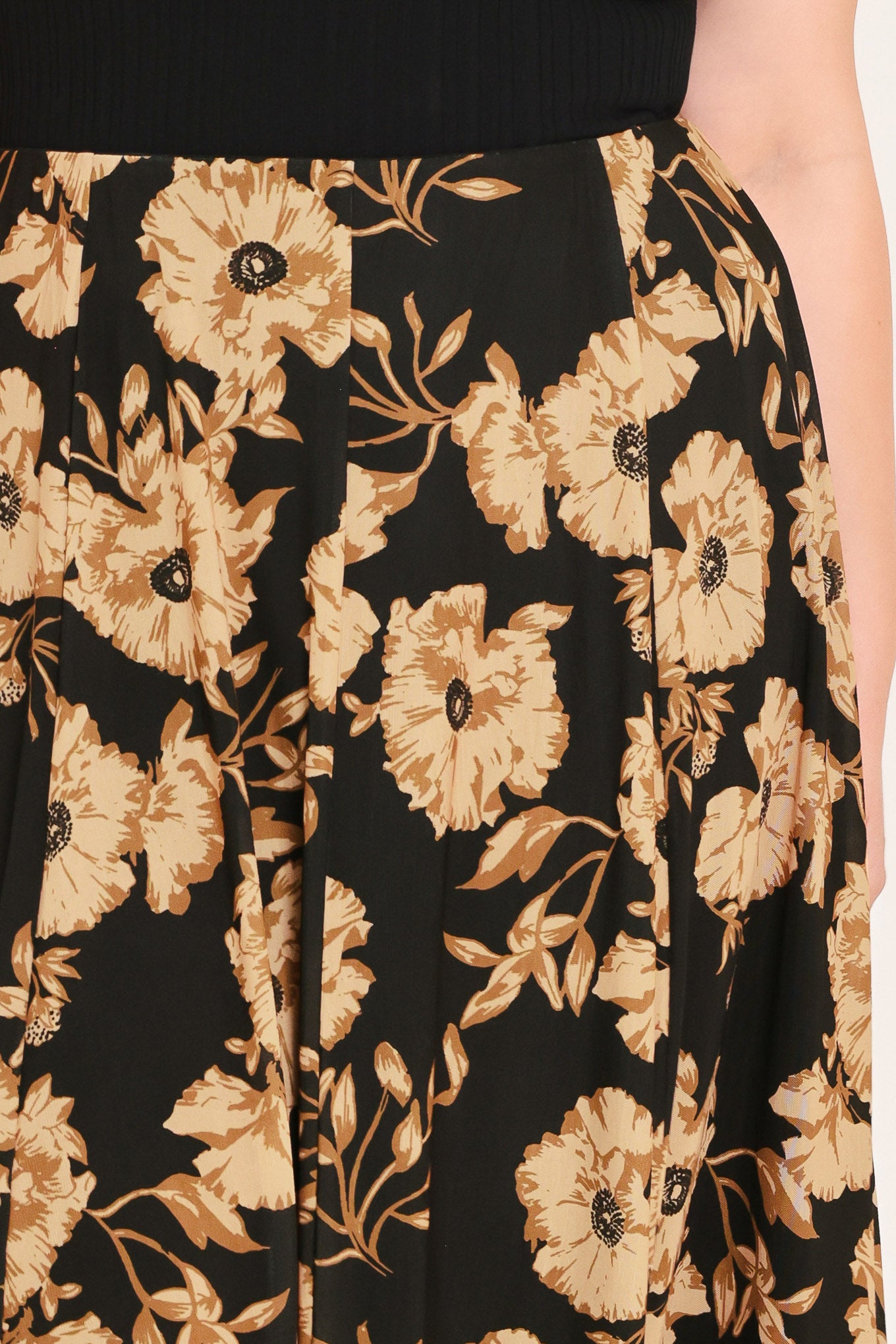 A woman modeling a sleeveless black top paired with a long black skirt featuring a large beige floral print | Plus Curve Flying Tomato