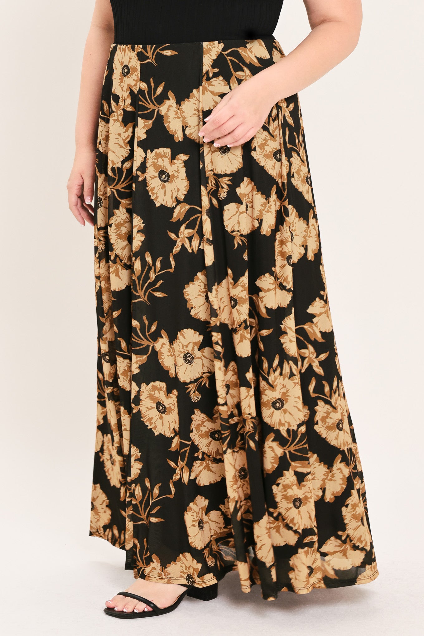 A woman modeling a sleeveless black top paired with a long black skirt featuring a large beige floral print | Plus Curve Flying Tomato