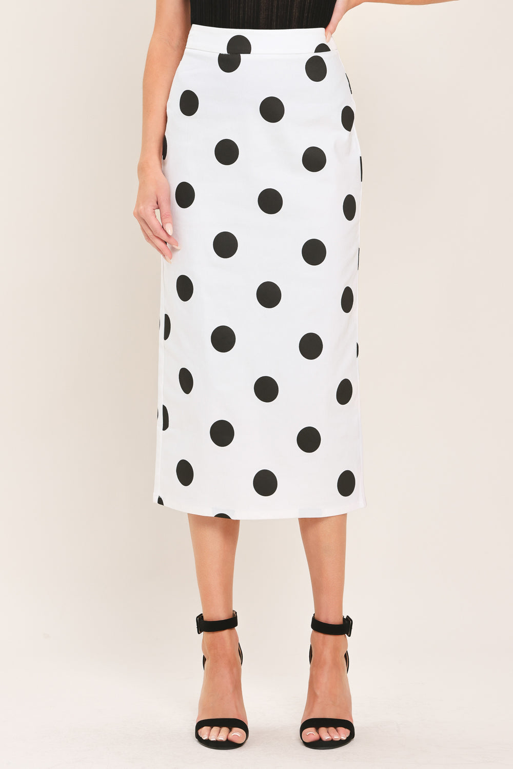 A woman wearing a white midi pencil skirt with large black polka dots | Flying Tomato