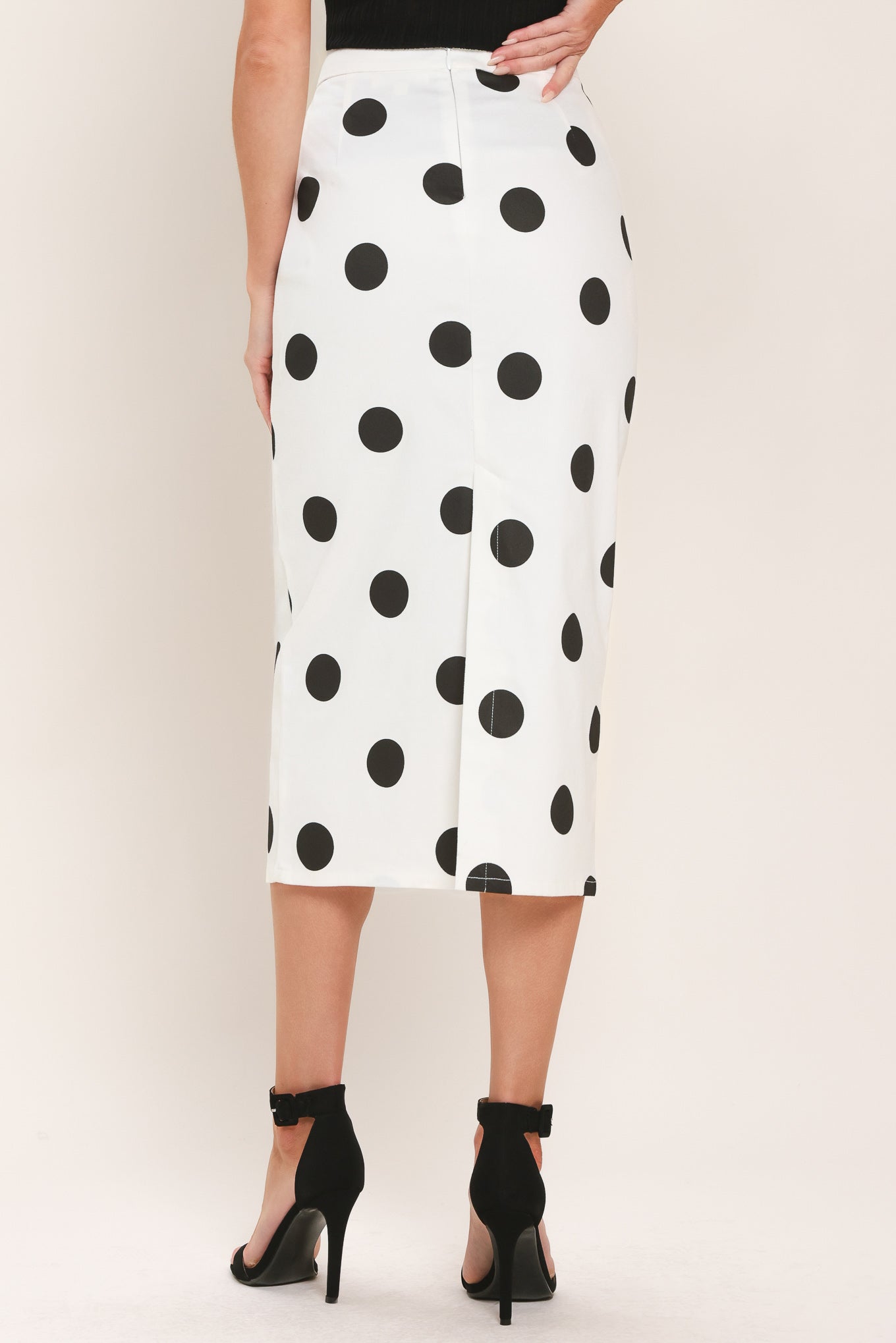 A woman wearing a white midi pencil skirt with large black polka dots | Flying Tomato