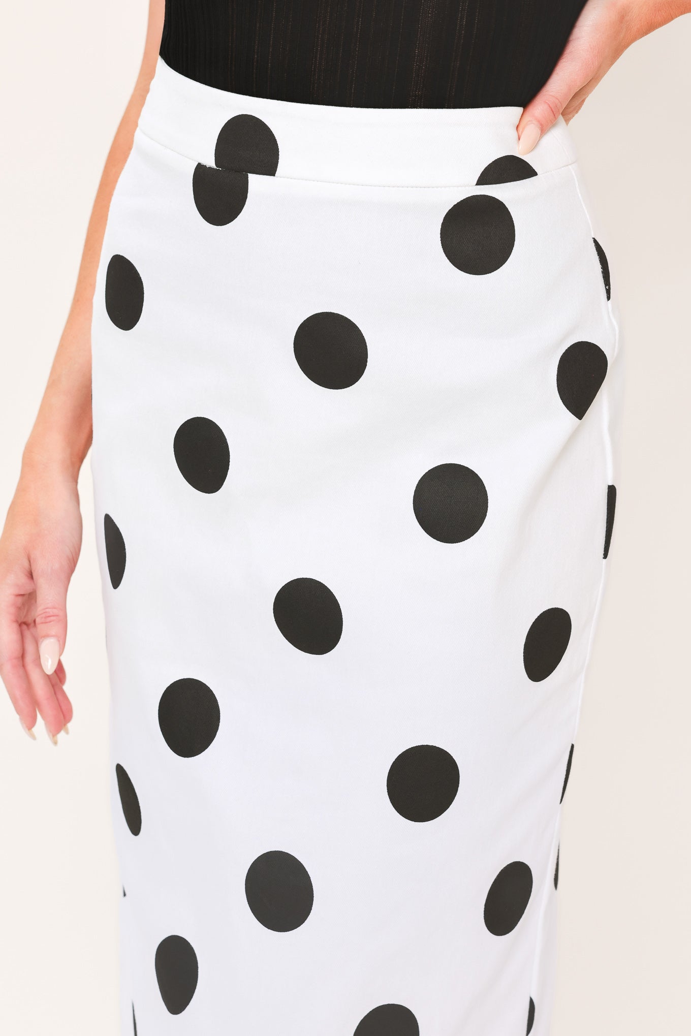 A woman wearing a white midi pencil skirt with large black polka dots | Flying Tomato