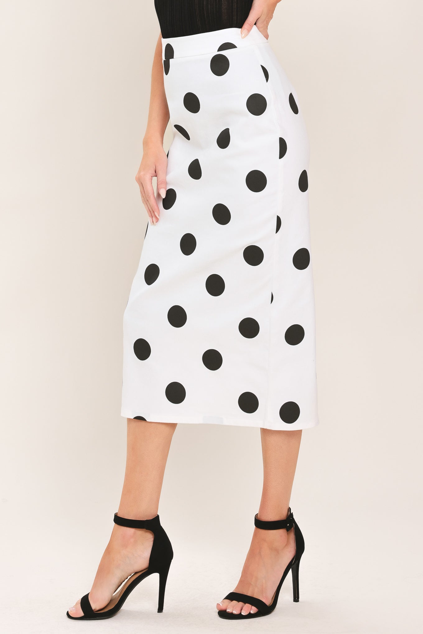 A woman wearing a white midi pencil skirt with large black polka dots | Flying Tomato