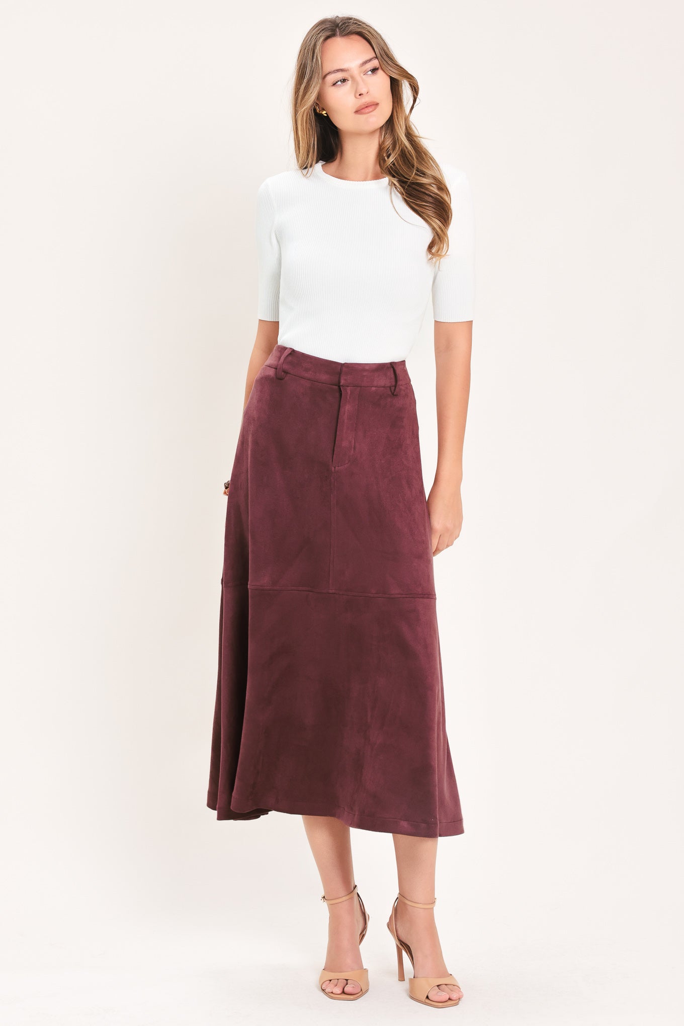 A woman modeling a high-waisted, midi A-line skirt in a deep burgundy suede-like fabric | Flying Tomato