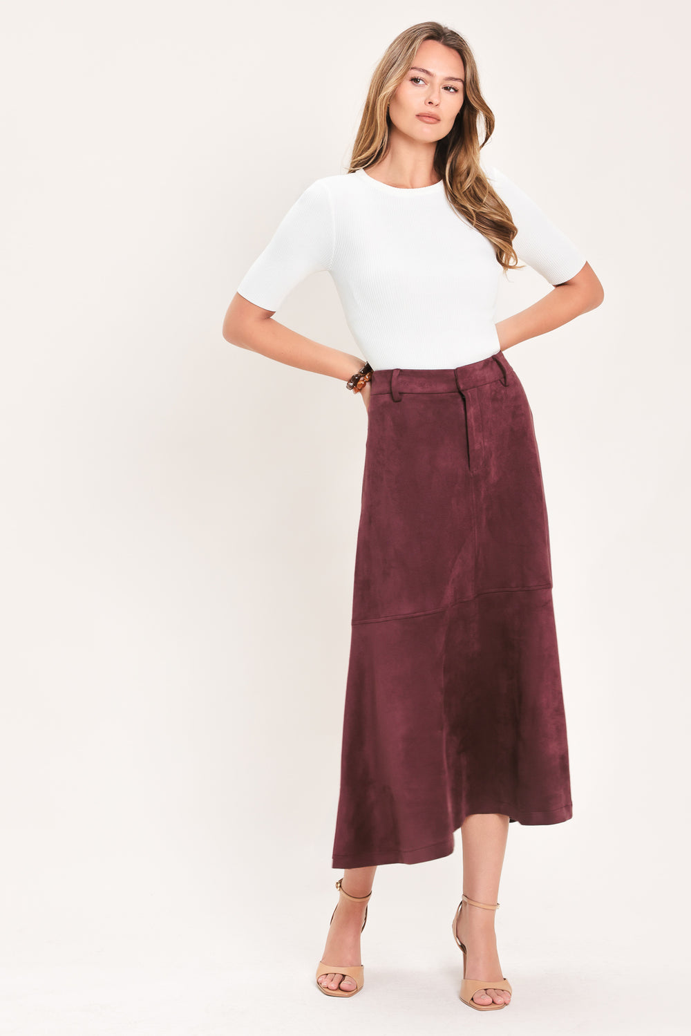 A woman modeling a high-waisted, midi A-line skirt in a deep burgundy suede-like fabric | Flying Tomato