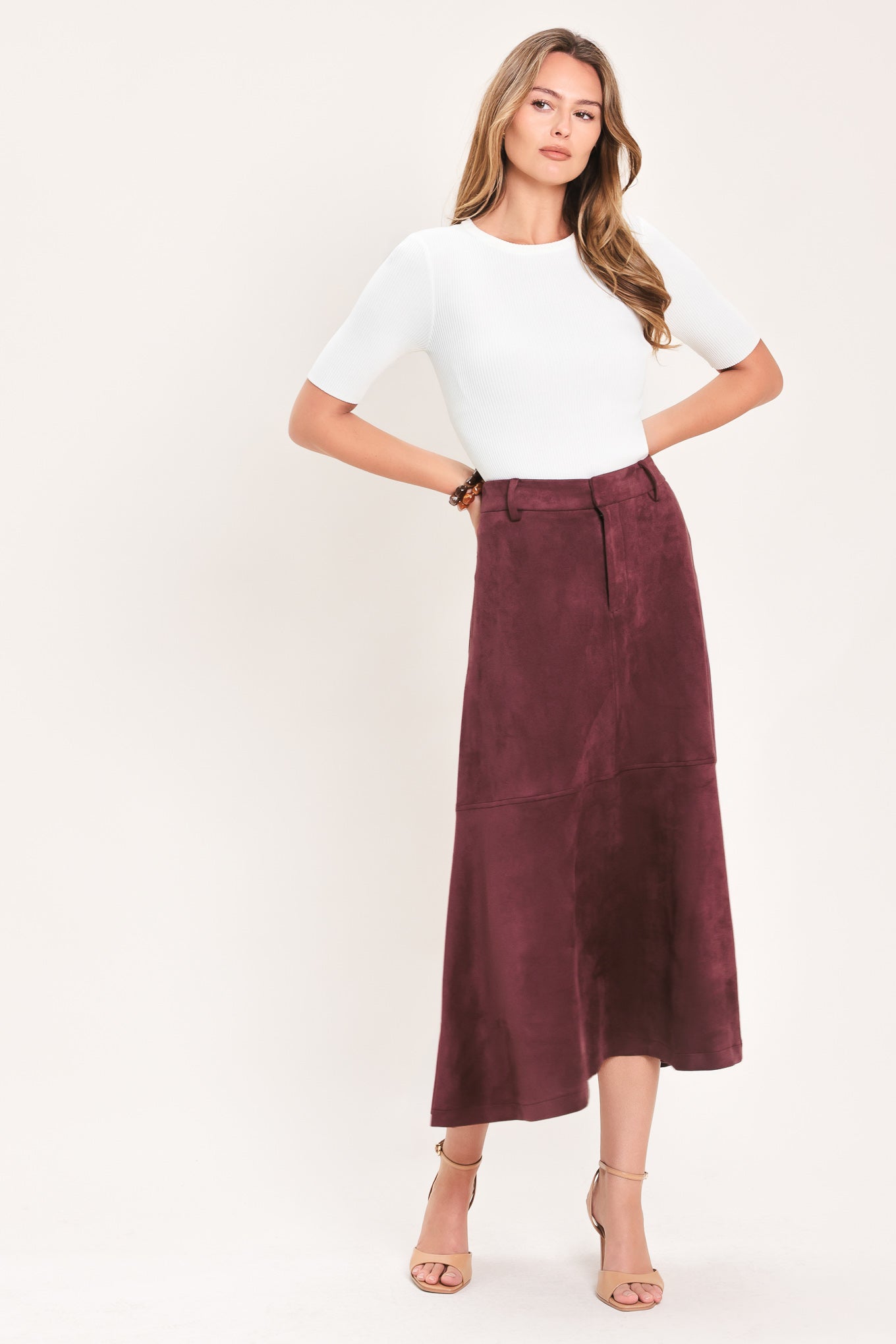 A woman modeling a high-waisted, midi A-line skirt in a deep burgundy suede-like fabric | Flying Tomato