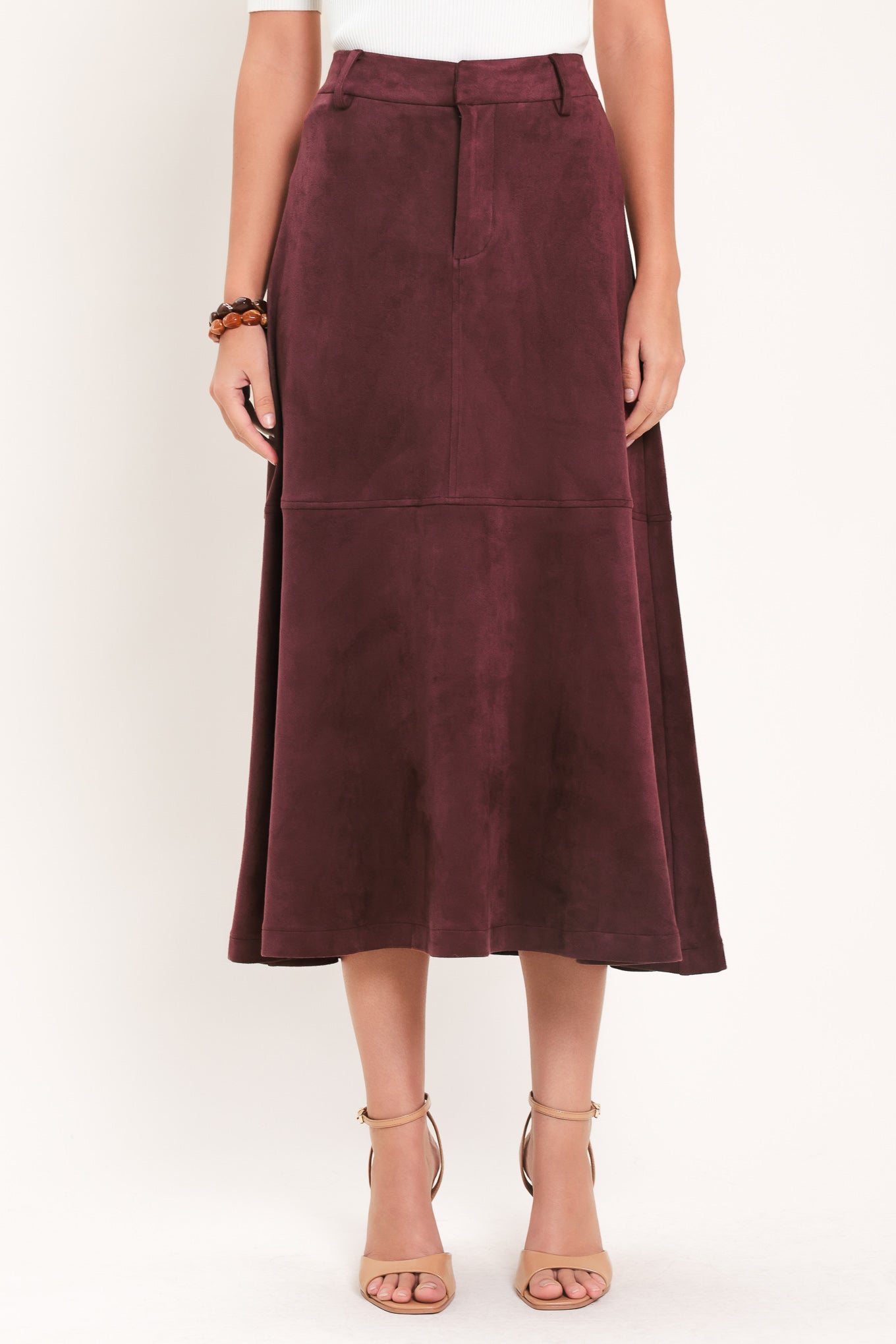 A woman modeling a high-waisted, midi A-line skirt in a deep burgundy suede-like fabric | Flying Tomato