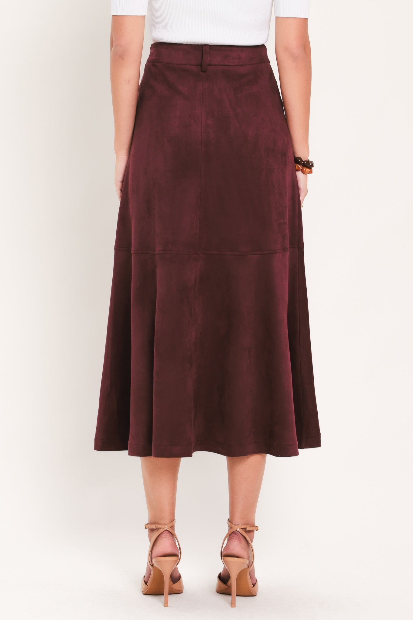 A woman modeling a high-waisted, midi A-line skirt in a deep burgundy suede-like fabric | Flying Tomato