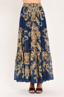 A navy blue tiered maxi skirt with an ornate gold and brown baroque damask pattern, shown on a model | Flying Tomato