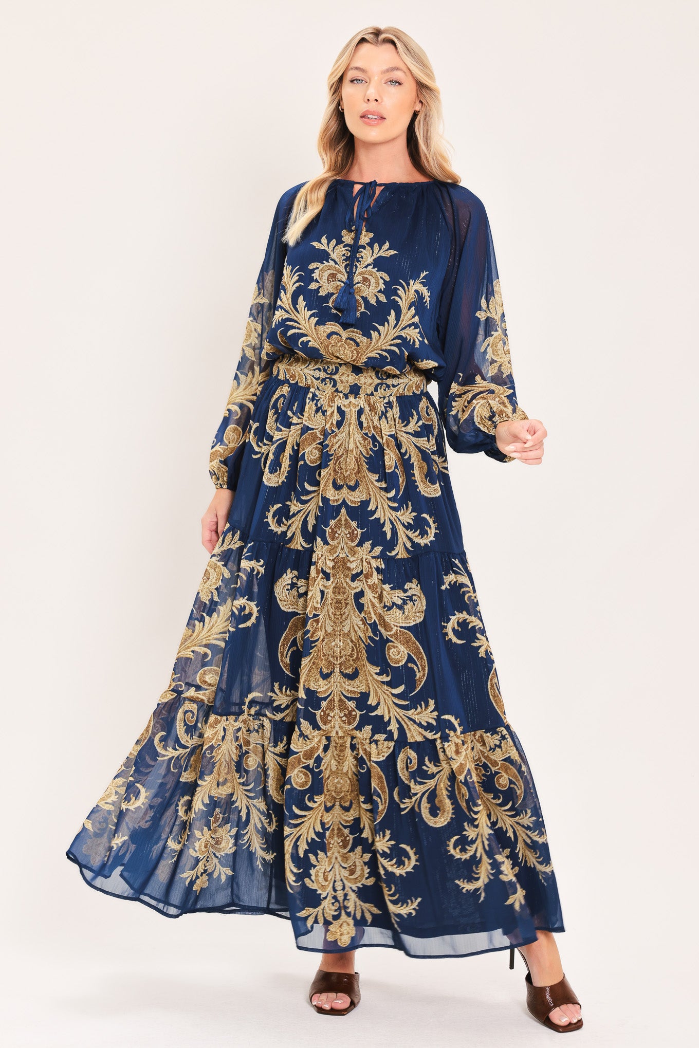 A navy blue tiered maxi skirt with an ornate gold and brown baroque damask pattern, shown on a model | Flying Tomato