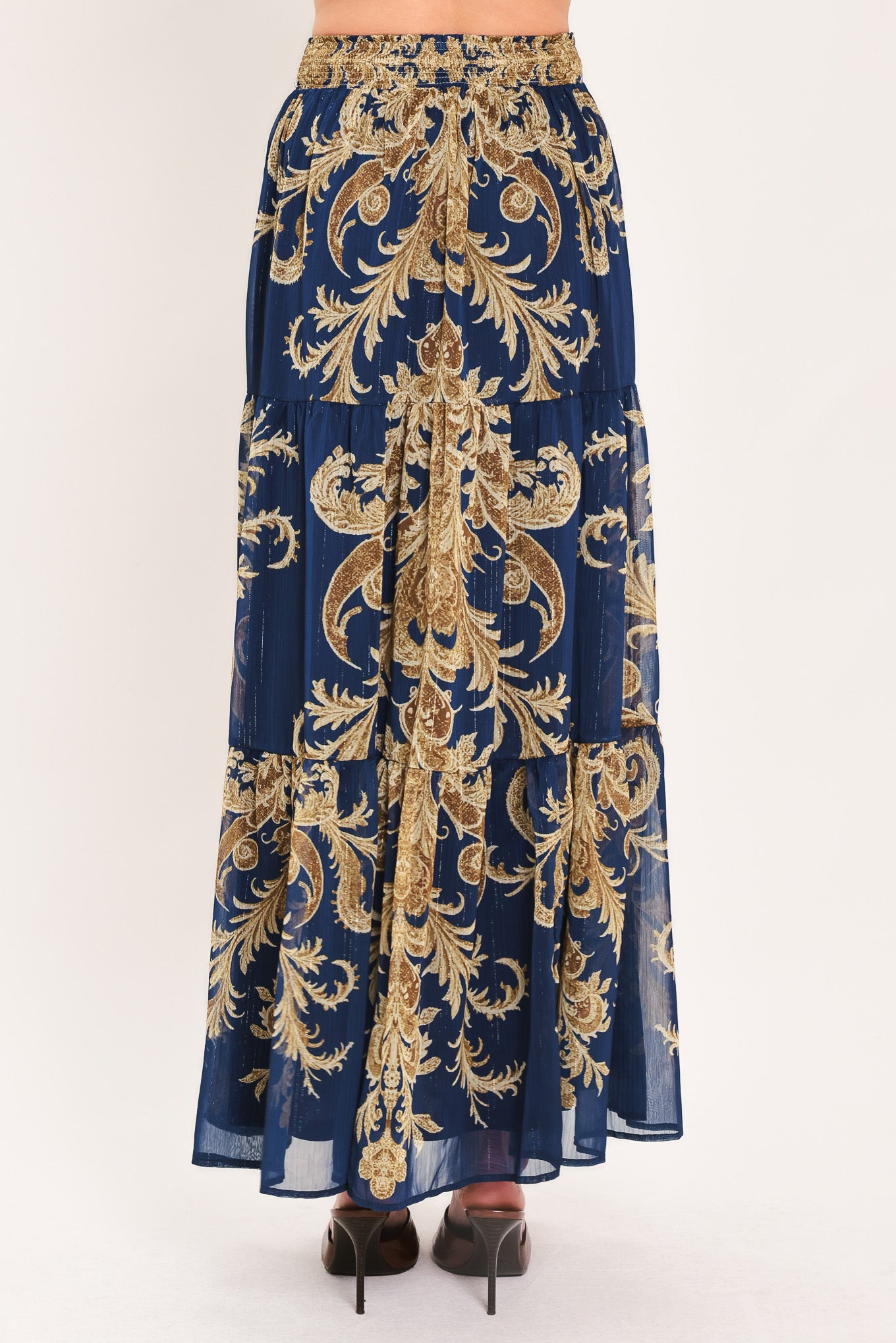 A navy blue tiered maxi skirt with an ornate gold and brown baroque damask pattern, shown on a model | Flying Tomato