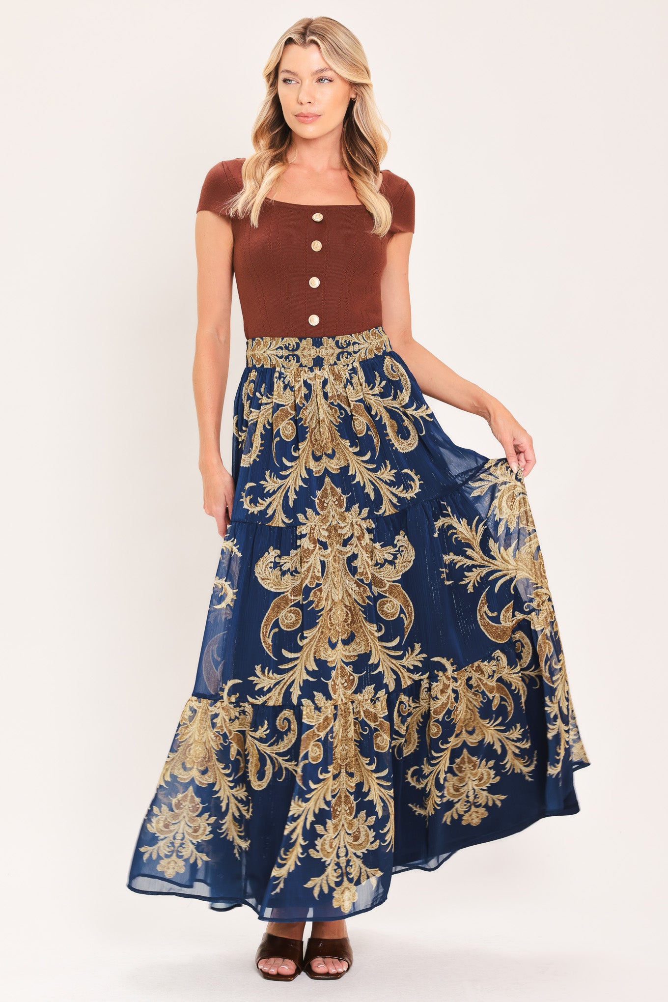 A navy blue tiered maxi skirt with an ornate gold and brown baroque damask pattern, shown on a model | Flying Tomato