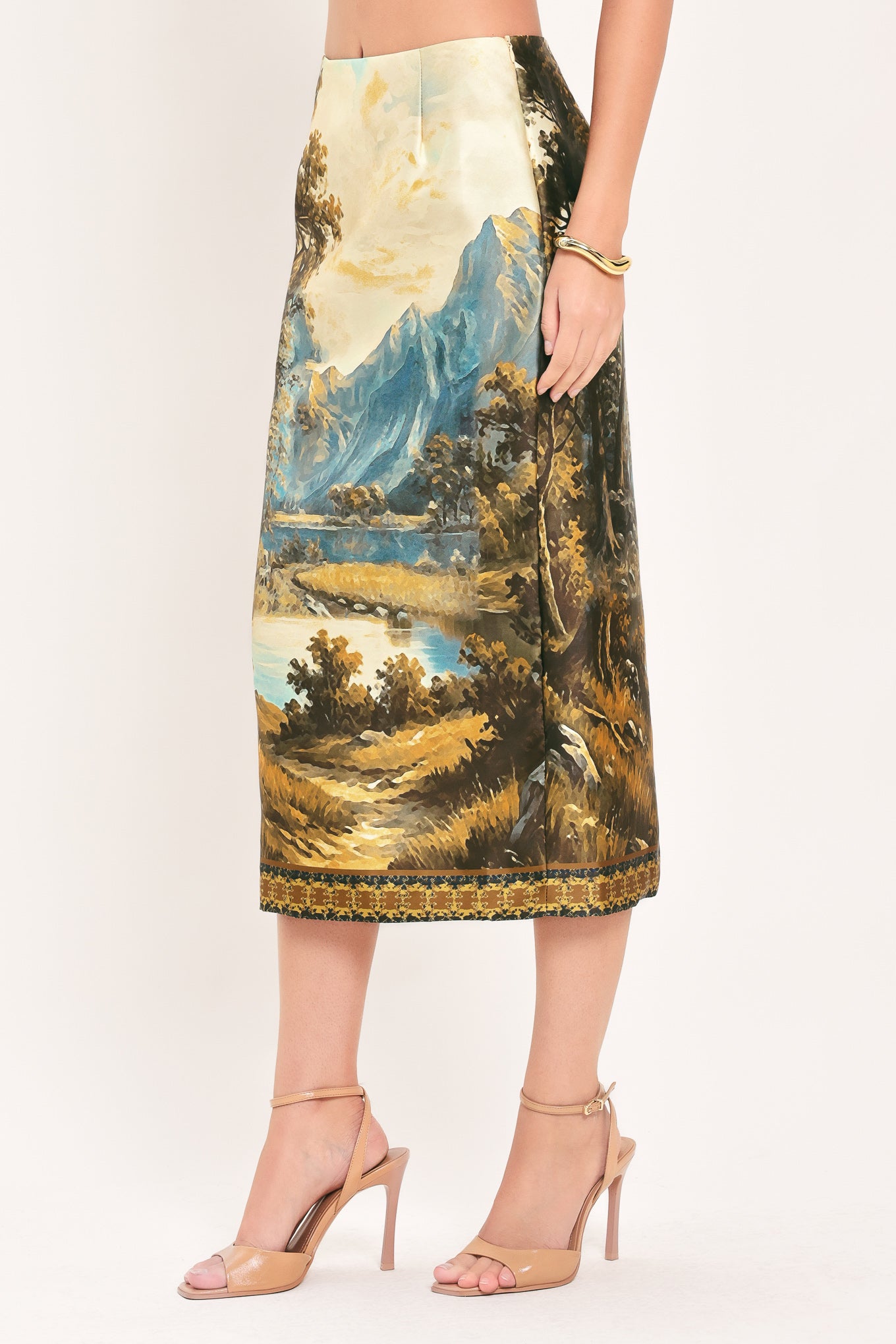 A model wearing a high-waisted midi skirt with a detailed landscape print of mountains, lakes, and trees | Flying Tomato