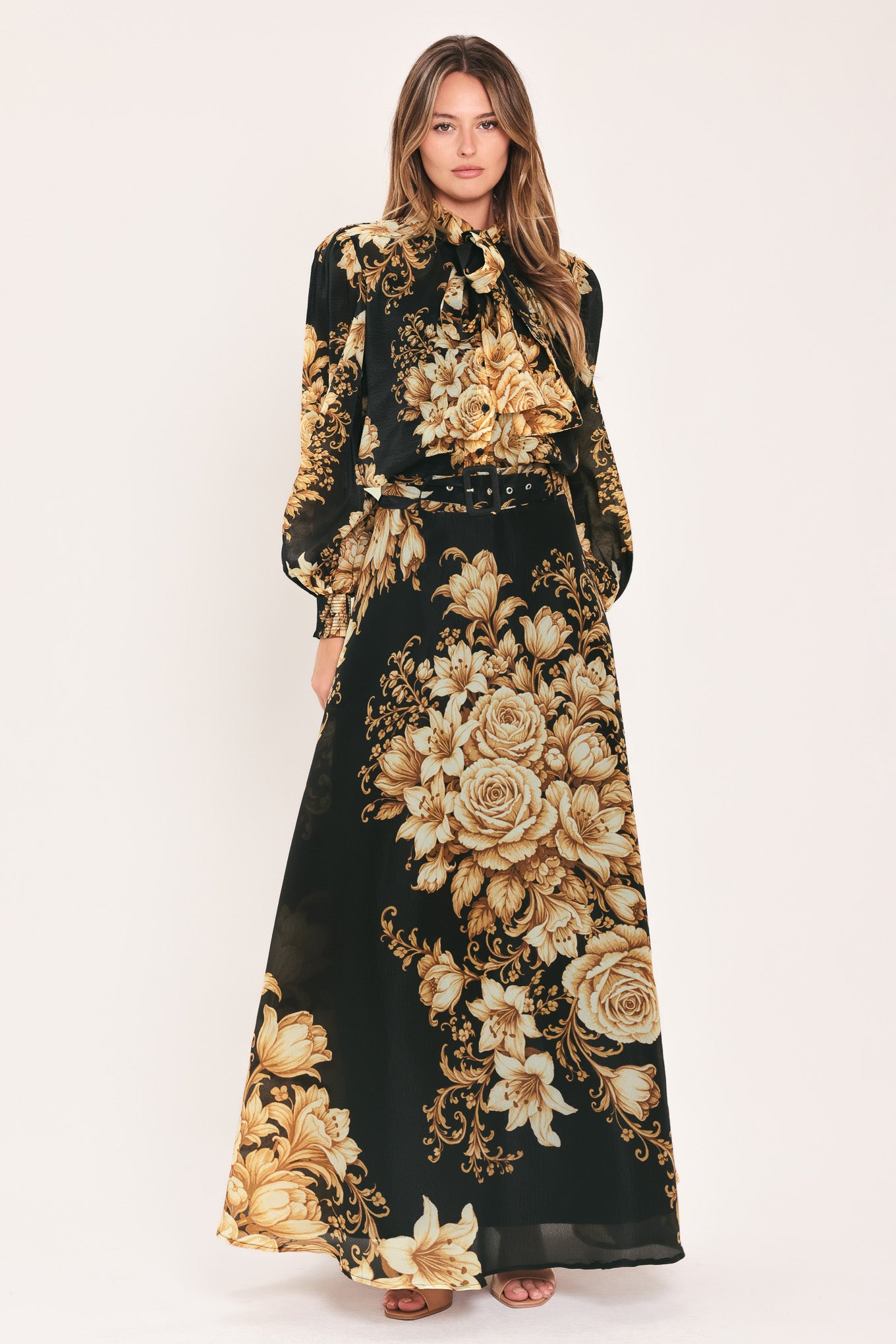 A woman wearing a flowing black maxi skirt with a large beige and gold floral print | Flying Tomato