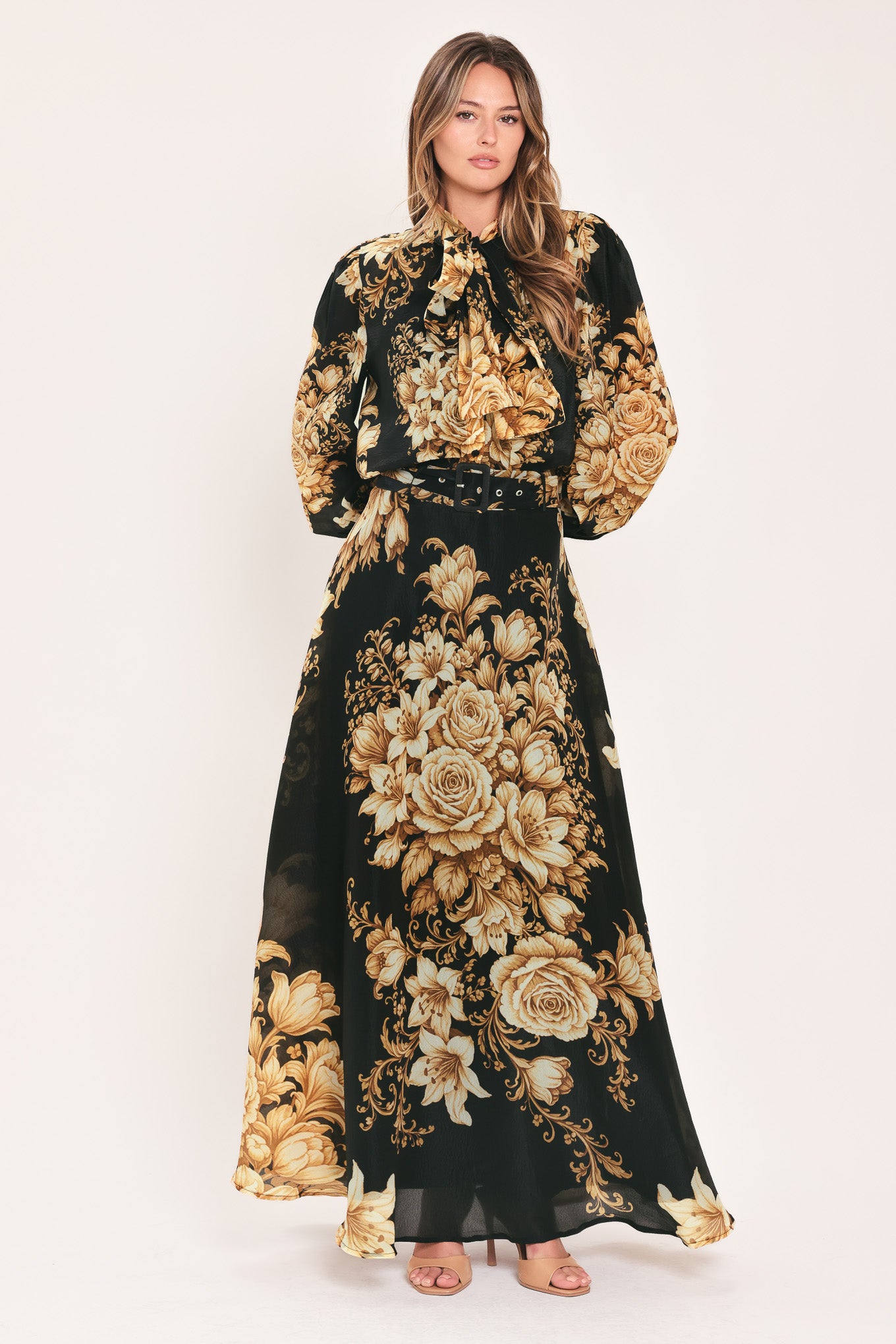 A woman wearing a flowing black maxi skirt with a large beige and gold floral print | Flying Tomato
