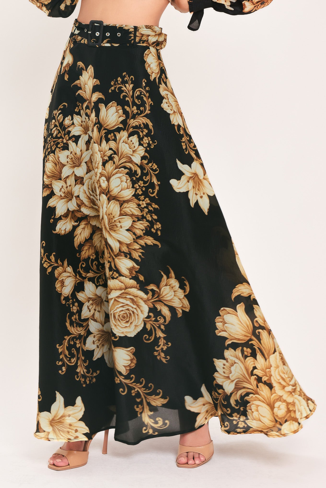 A woman wearing a flowing black maxi skirt with a large beige and gold floral print | Flying Tomato