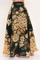 A woman wearing a flowing black maxi skirt with a large beige and gold floral print | Flying Tomato