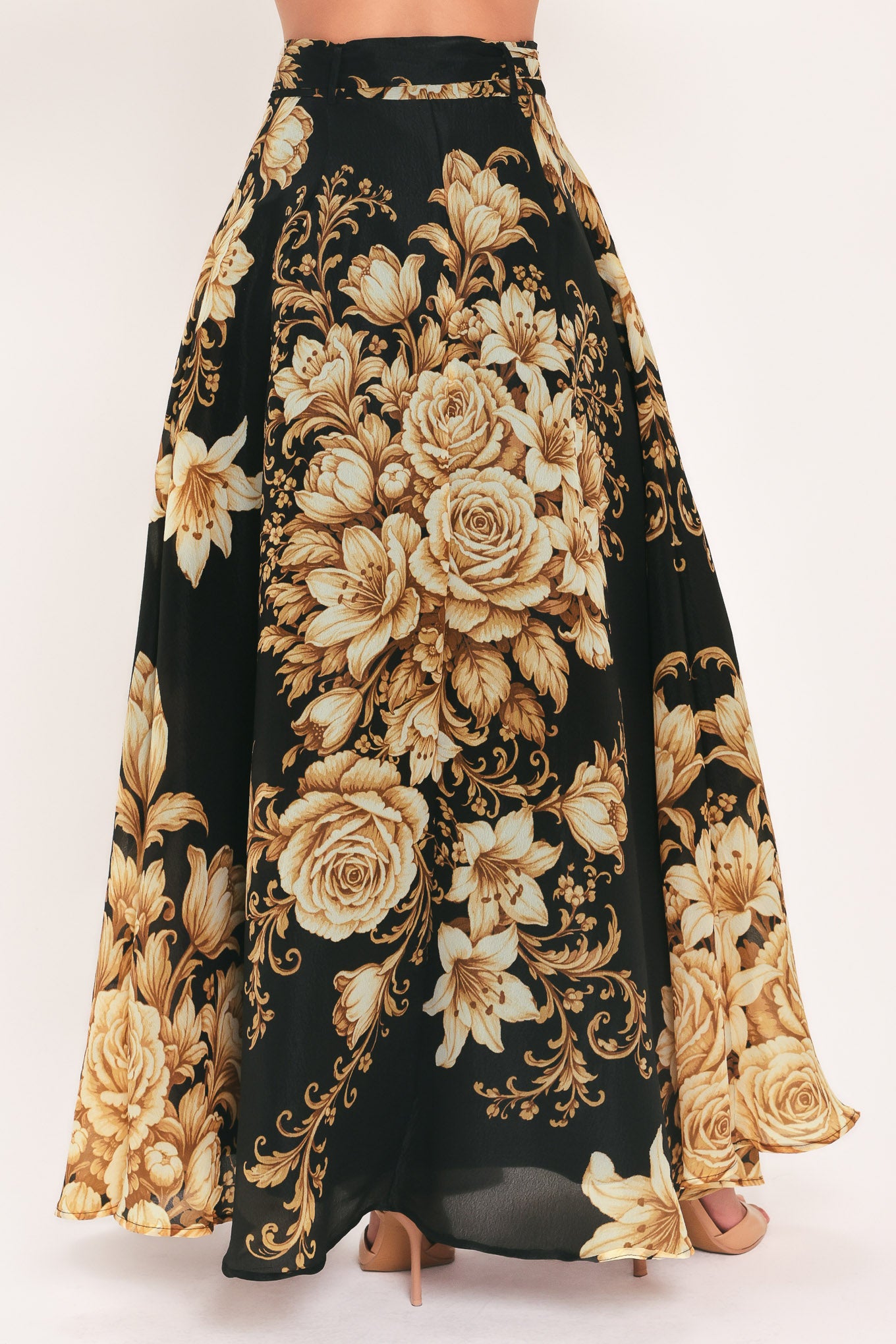A woman wearing a flowing black maxi skirt with a large beige and gold floral print | Flying Tomato