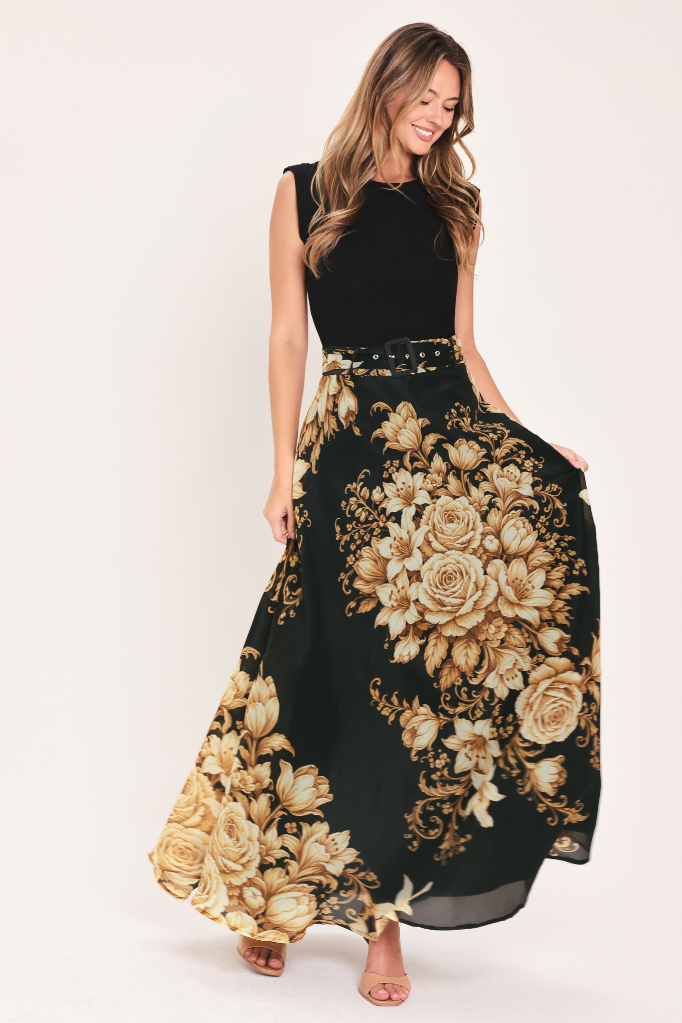 A woman wearing a flowing black maxi skirt with a large beige and gold floral print | Flying Tomato