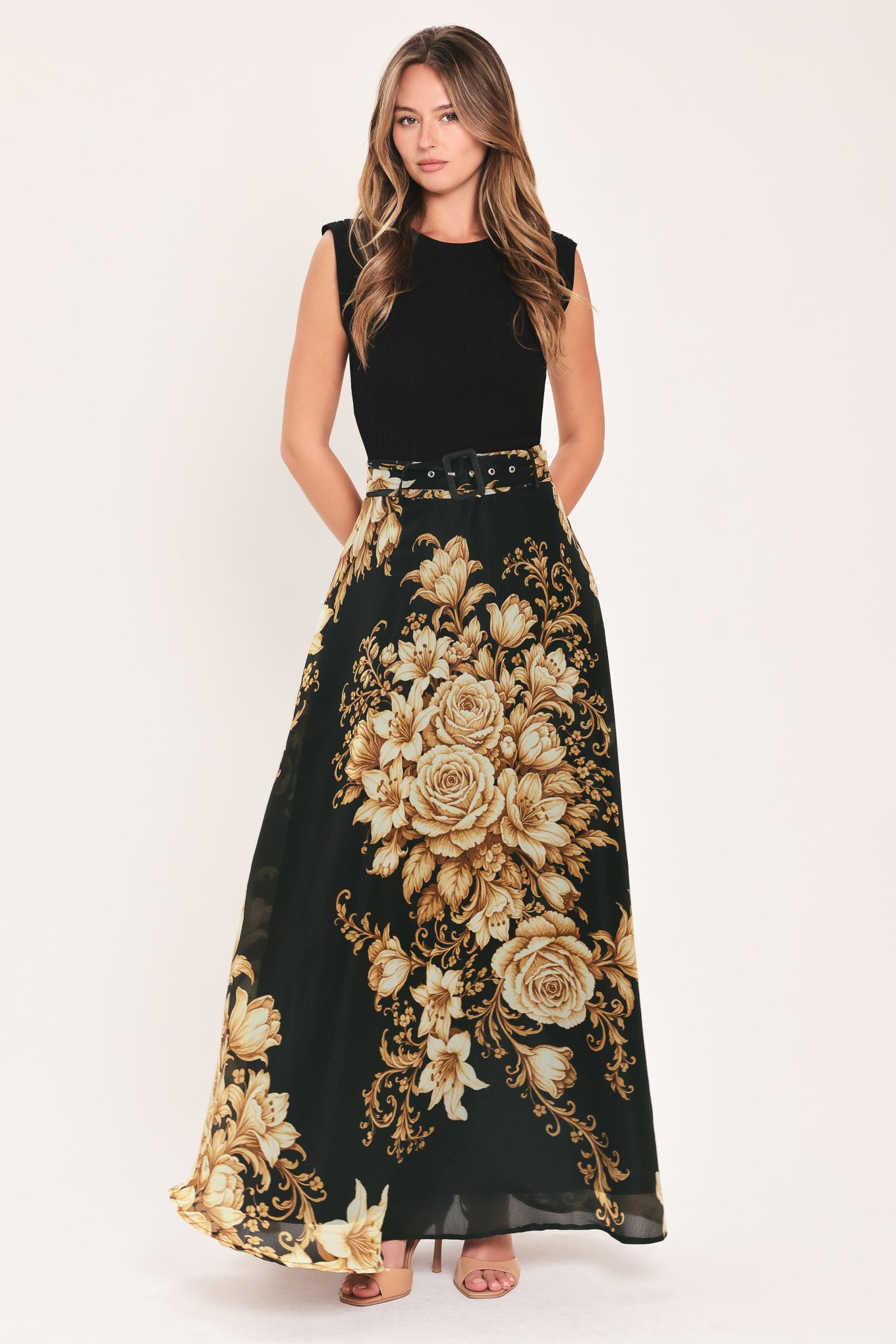 A woman wearing a flowing black maxi skirt with a large beige and gold floral print | Flying Tomato