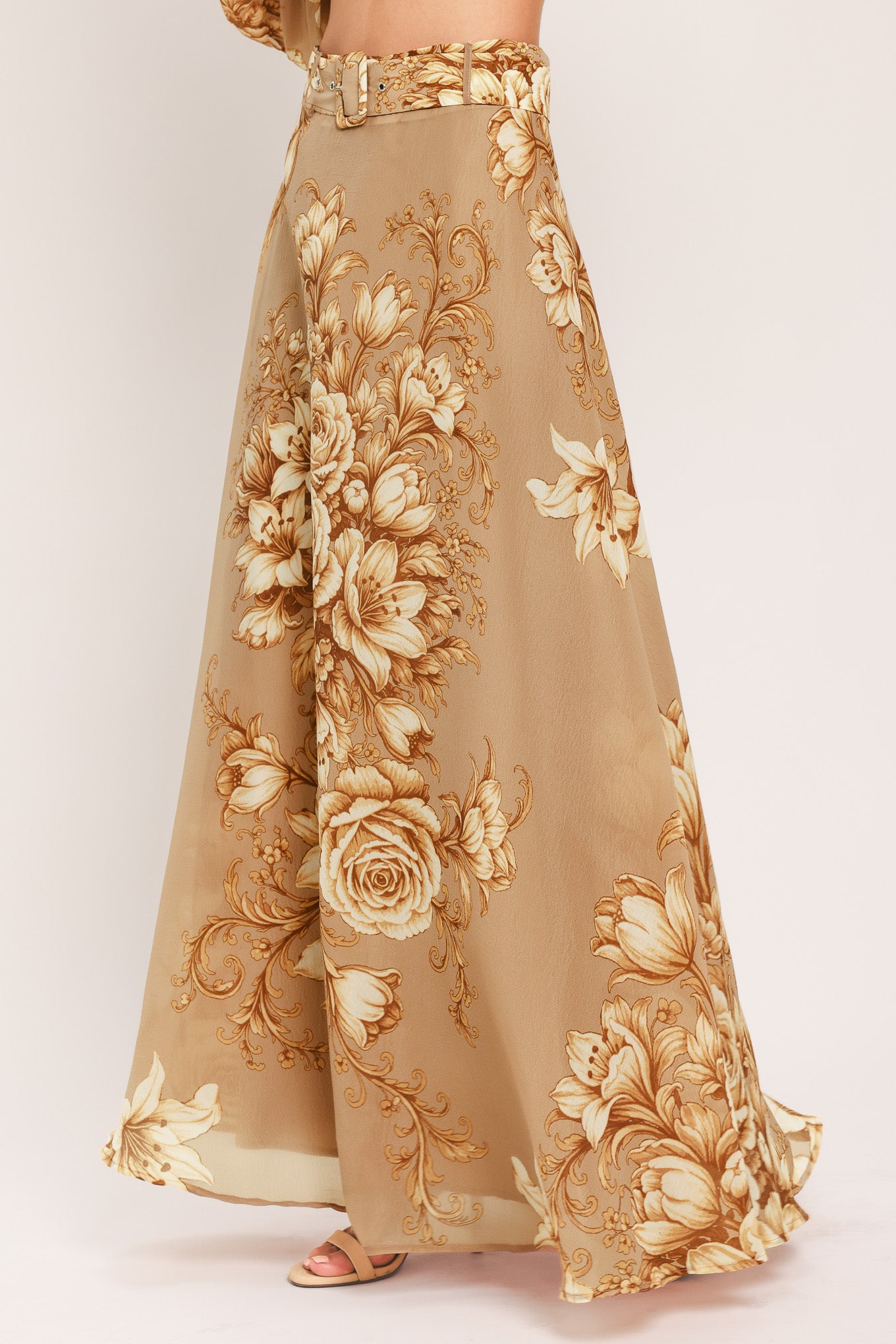 A floor-length beige skirt with a large gold and cream floral rose pattern, featuring a matching beaded belt, shown on a model | Flying Tomato