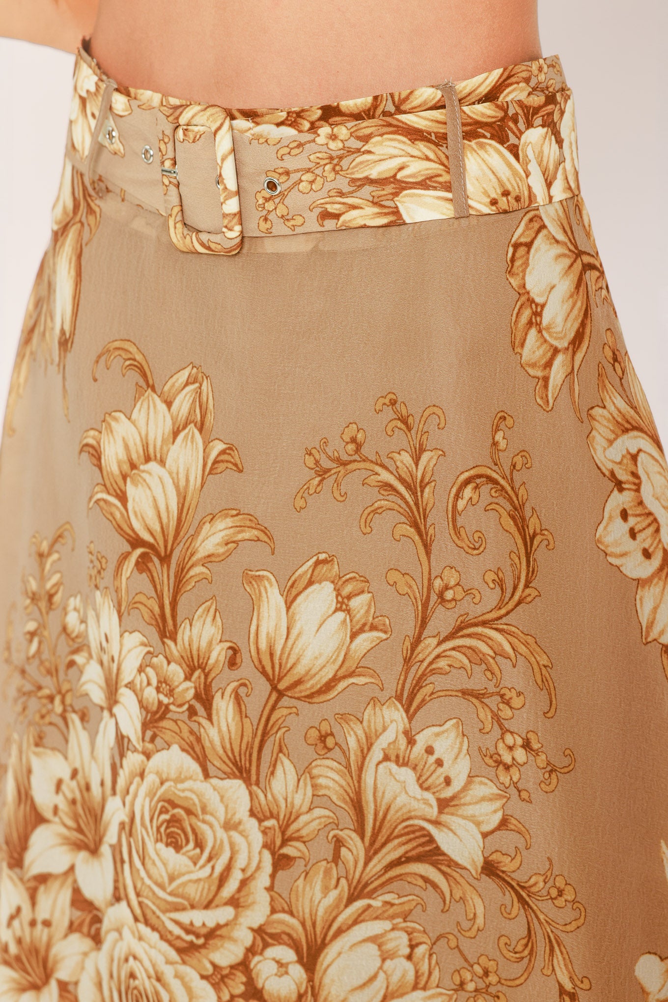 A floor-length beige skirt with a large gold and cream floral rose pattern, featuring a matching beaded belt, shown on a model | Flying Tomato